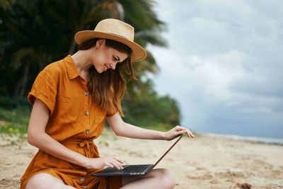 Young woman using mobile phone while sitting on land