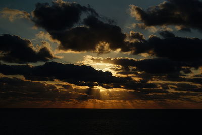 Scenic view of sea against dramatic sky during sunset