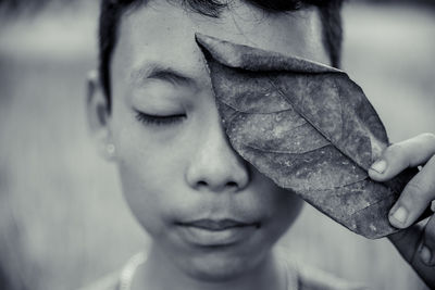 Close-up portrait of boy holding leaf
