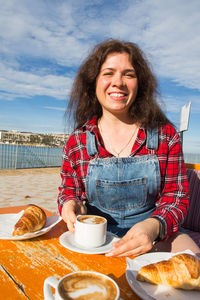Portrait of a smiling young woman sitting at table