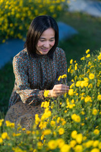 Young woman with yellow flowers on field