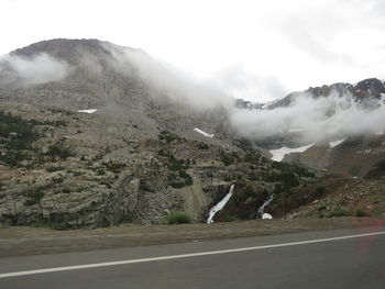 Scenic view of road by mountains against sky