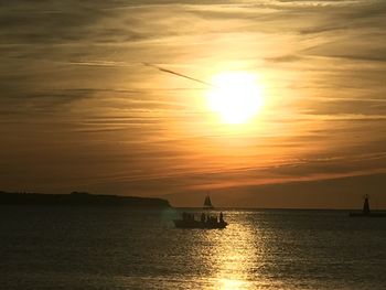 Silhouette sailboat in sea against sky during sunset