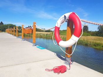 Red flags hanging on riverbank against blue sky