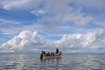 People sitting on boat in sea against sky