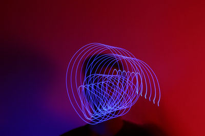 Close-up of illuminated light painting against red background