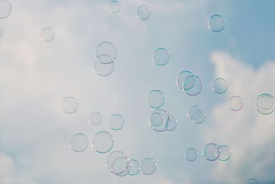 Close-up of water drops on rainbow against sky