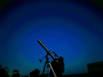 Low angle view of man against blue sky at night