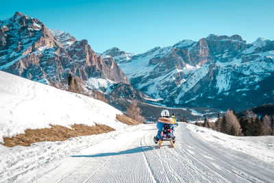 People riding motorcycle on snowcapped mountains against sky