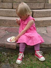 Full length of girl eating dessert while sitting on steps