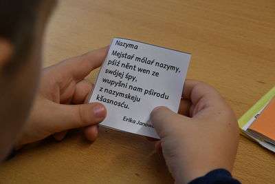 High angle view of hand holding book on table