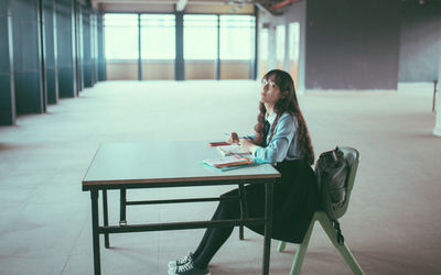 Side view of woman sitting on table