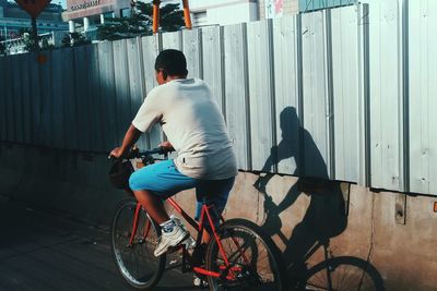 Man cycling on street by wall