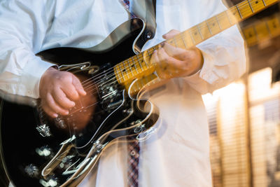 Midsection of man playing guitar