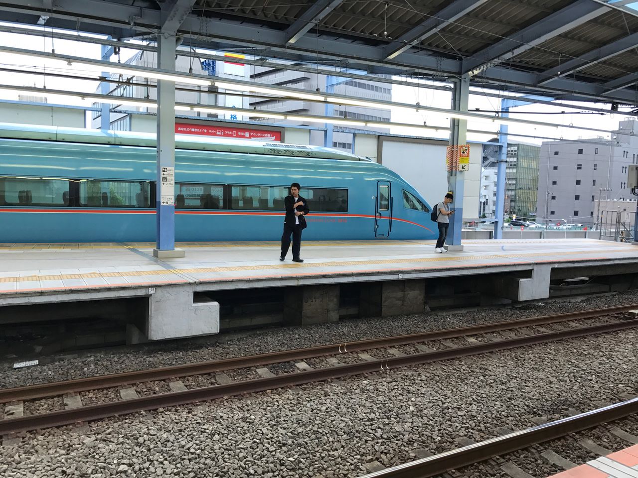 railroad track, rail transportation, transportation, public transportation, real people, railroad station, railroad station platform, railway track, one person, platform, mode of transport, men, waiting, lifestyles, day, standing, train - vehicle, full length, women, outdoors, people