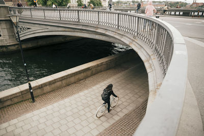 High angle view of businesswoman cycling on footpath by canal in city