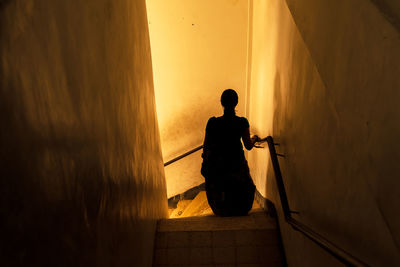 Rear view of silhouette woman standing against wall