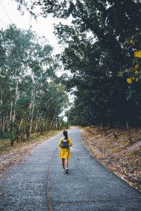 Woman walking on road amidst trees