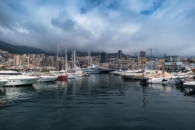 Sailboats moored on harbor against sky