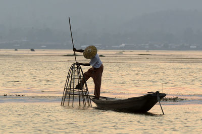 Fisherman fishing in lake during sunset