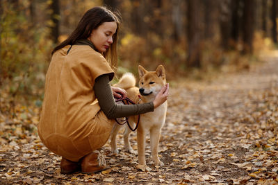 Beautiful woman walking shiba inu dog in fall forest. autumn mood