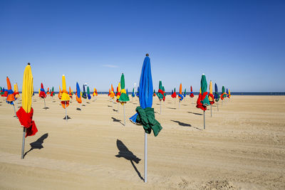 Panoramic view of beach umbrellas against clear blue sky