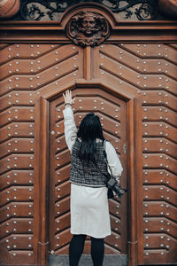 Rear view of woman standing against door