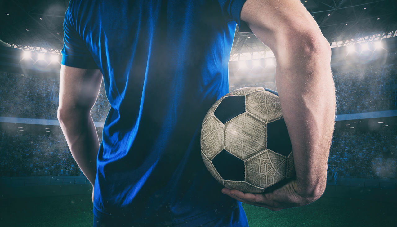 LOW ANGLE VIEW OF MAN PLAYING SOCCER BALL ON FIELD