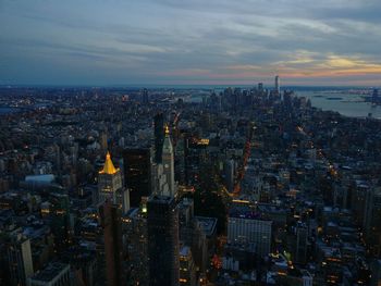 High angle view of illuminated city buildings against sky during sunset