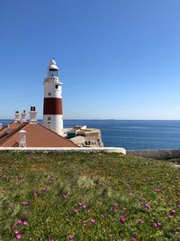 Lighthouse by sea against sky