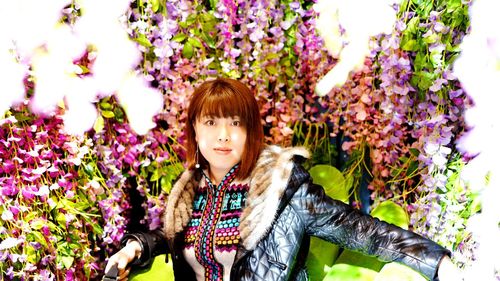 Portrait of woman standing by purple flowering plants