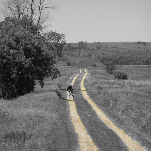 transportation, land vehicle, riding, mode of transport, road, bicycle, lifestyles, men, landscape, leisure activity, full length, cycling, dirt road, the way forward, on the move, clear sky, walking, tree