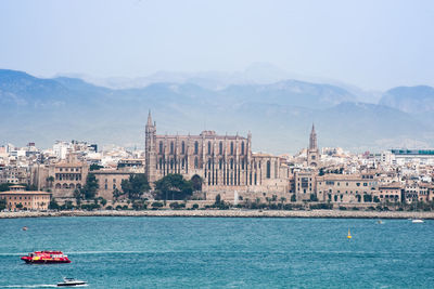 Boats in sea with city in background