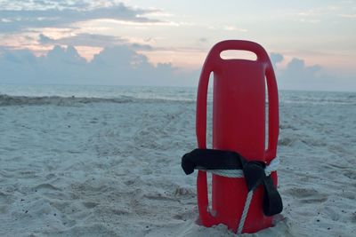 Red umbrella on beach against sky during sunset