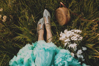 Low section of woman with pink flower on field