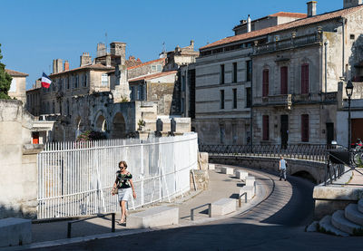 Woman on building in city against sky