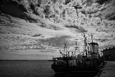 Sailboats moored on sea against sky