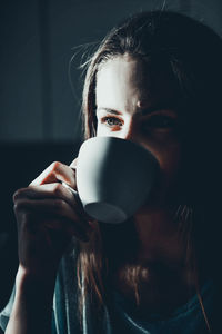 Close-up of thoughtful woman drinking coffee at home