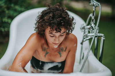 Young woman sitting in bathtub outdoors