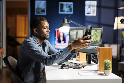 Young woman using mobile phone at table