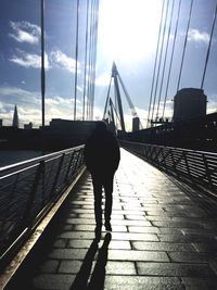 Rear view of silhouette man walking on bridge