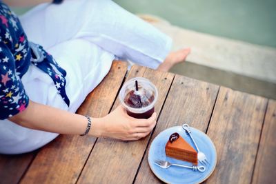 High angle view of woman holding coffee cup on table