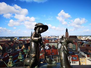 Statue in city against sky