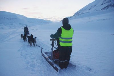 Man with dog sledding on snowy field