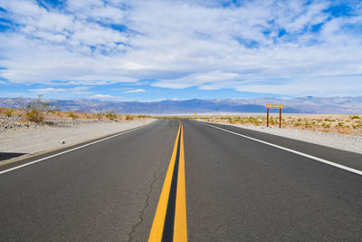 Road passing through landscape against cloudy sky