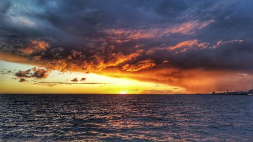 Scenic view of sea against dramatic sky during sunset