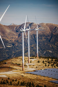 Windmills on field against mountain