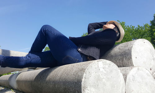 Woman lying on concrete against clear sky