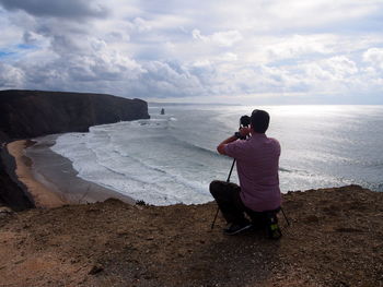 Rear view of man photographing sea against sky