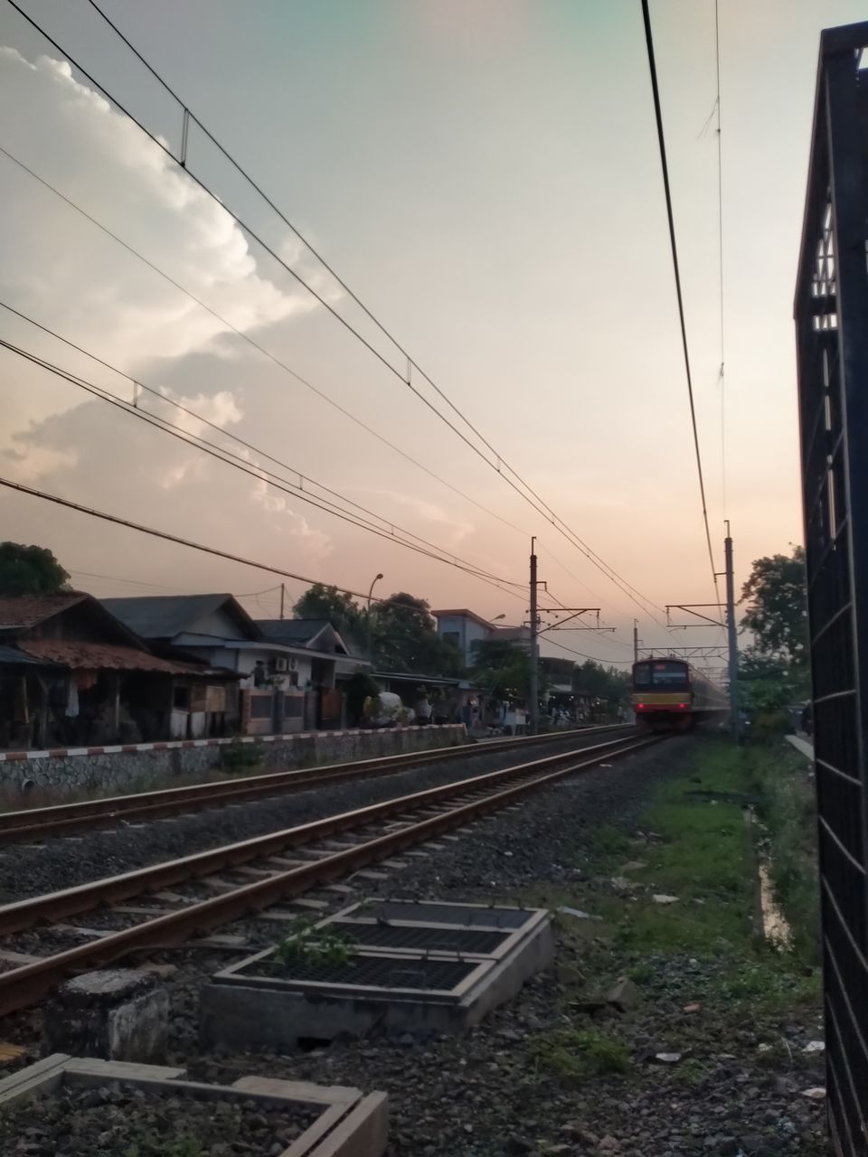 railroad track, track, rail transportation, transportation, sky, transport, mode of transportation, cable, railway, electricity, architecture, train, vehicle, nature, public transportation, power line, no people, cloud, sunset, urban area, travel, technology, city, built structure, power supply, residential area, electricity pylon, railroad station, outdoors, building exterior, land vehicle, railroad station platform, line